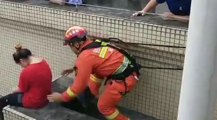 惊险！女子坐85米高楼顶欲轻生 消防员趁其不备将其一把抱下